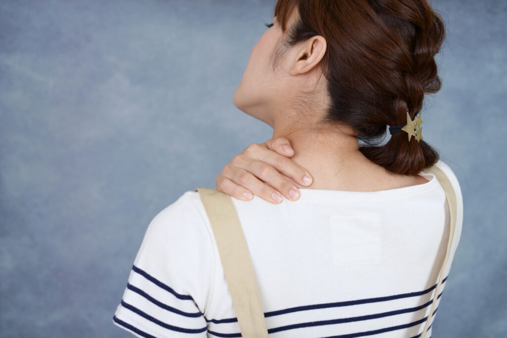 女性が肩こりに悩んでいる画像
