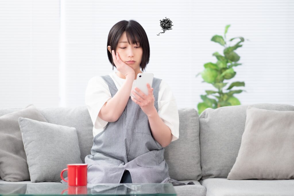 女性がスマホを持って何か悩んでいる