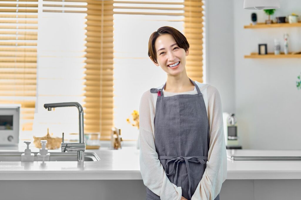 キッチンで微笑むエプロンの女性