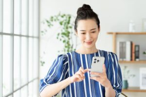 家でスマホを使う若い女性