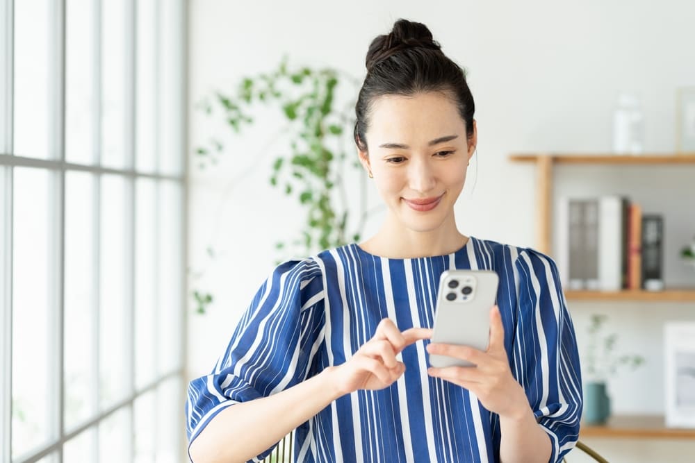家でスマホを使う若い女性